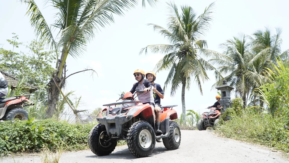 ATV convoy cruising along a tropical dirt trail under towering coconut palms